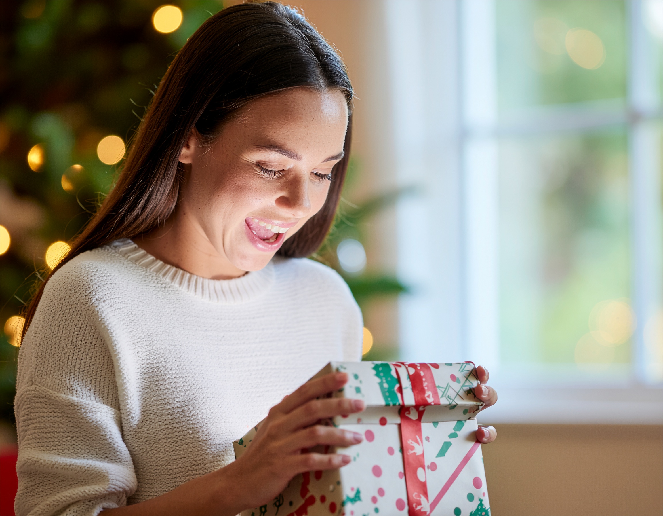 Smiling Woman in White Sweater Unwrapping a Gift